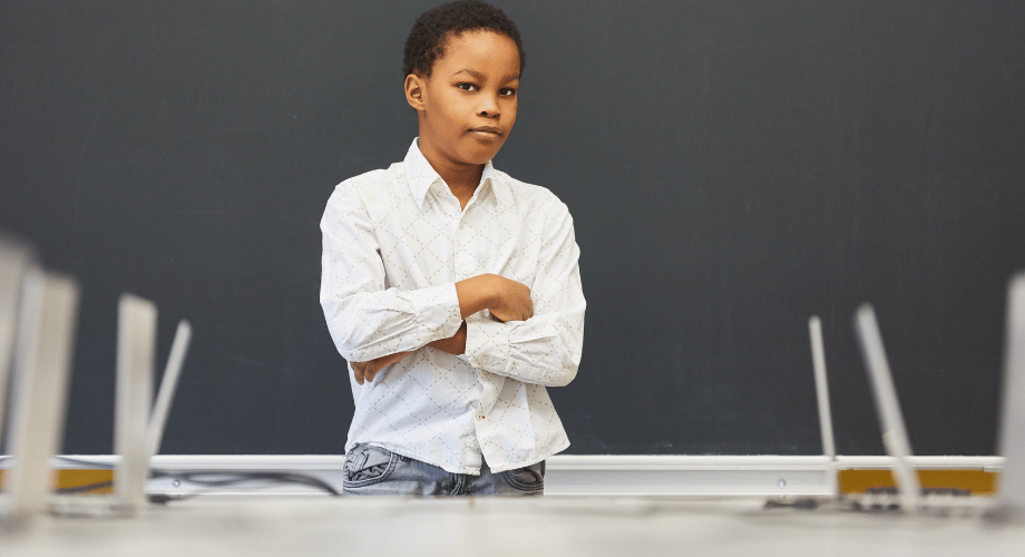 black student standing in front of the class full of laptops on top of the table