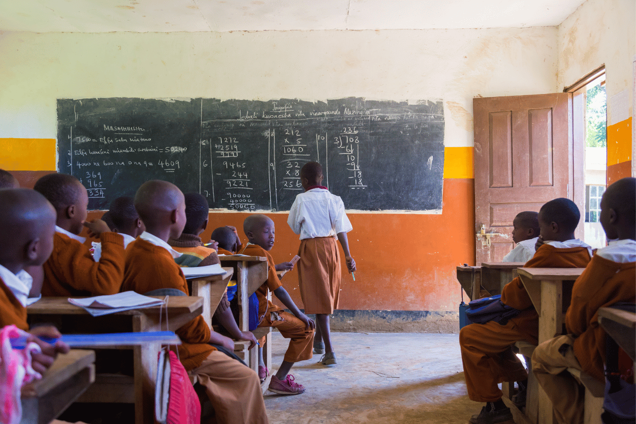 learners overflowing in the classroom , chalk board , benches