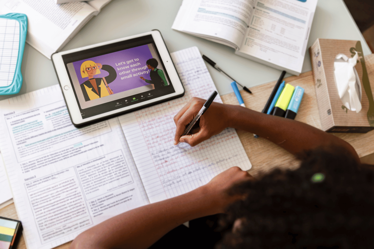 student writing notes on the exercise book , tablet device , pen and markers